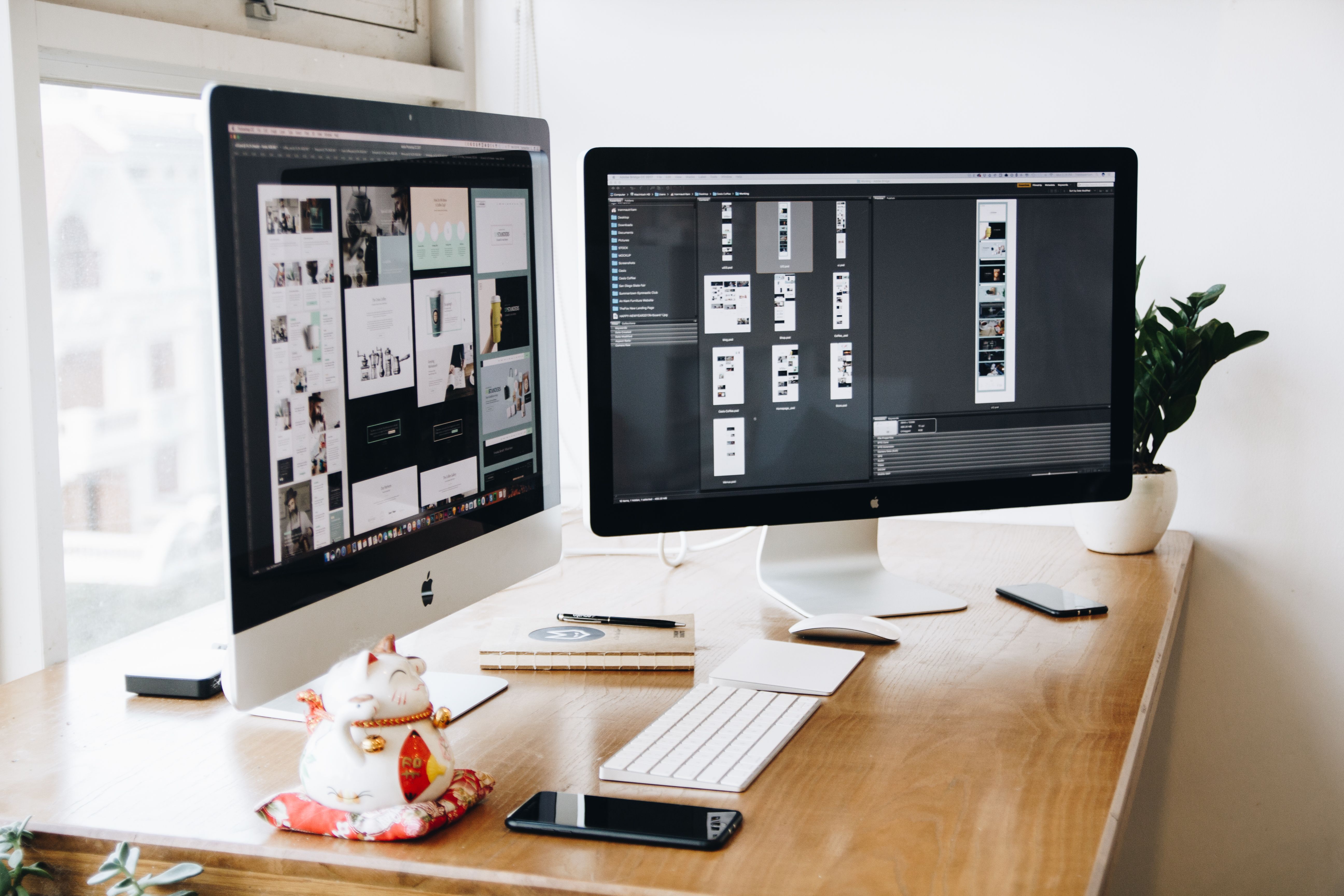 A studio desk with two screens showing website layouts in progress